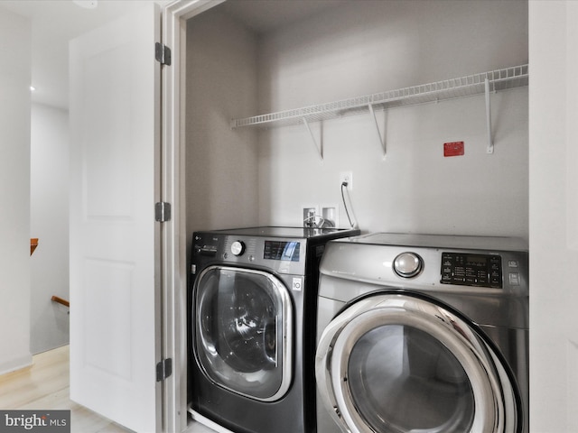 laundry area with laundry area, separate washer and dryer, and wood finished floors