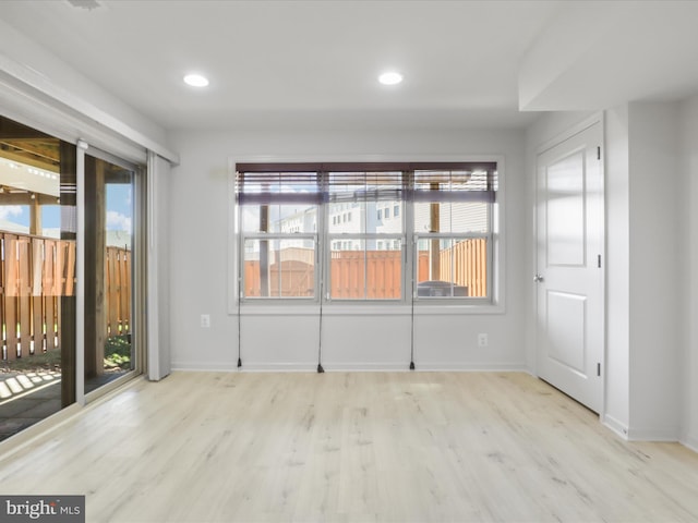 unfurnished room with a healthy amount of sunlight, baseboards, and wood finished floors