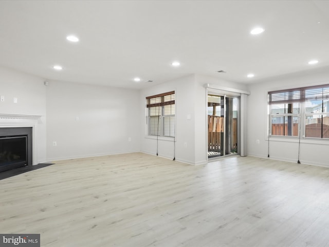 unfurnished living room with a fireplace with flush hearth, recessed lighting, and light wood finished floors