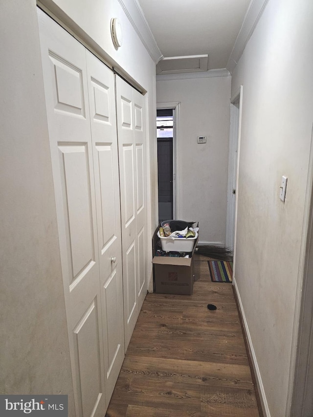 hallway featuring attic access, dark wood-style floors, baseboards, and ornamental molding