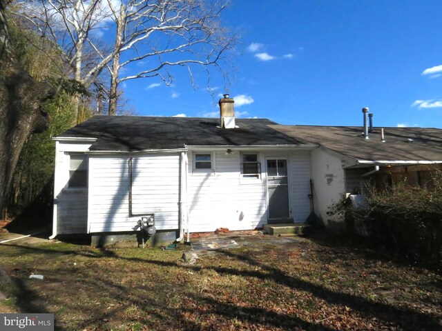 back of house featuring entry steps and a chimney