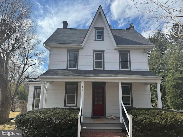 view of front of house with covered porch, roof with shingles, and a chimney