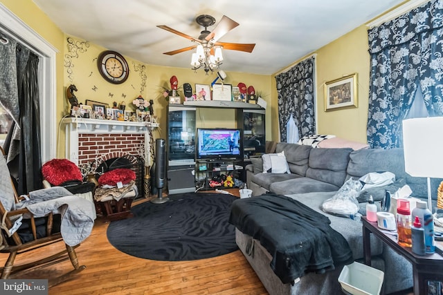 living area featuring ceiling fan, wood finished floors, and a fireplace