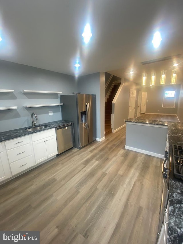 kitchen with light wood-style flooring, a sink, white cabinets, appliances with stainless steel finishes, and open shelves