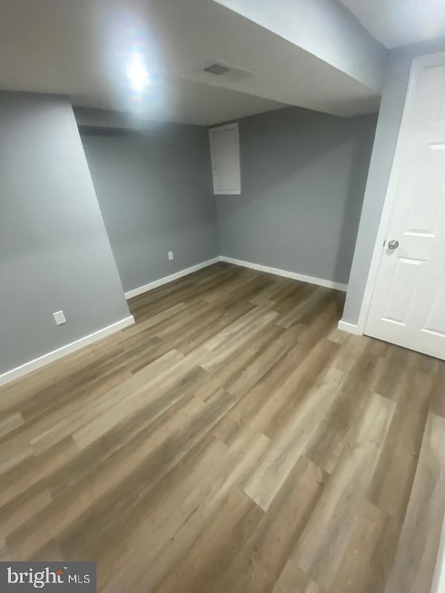 finished basement with wood finished floors, visible vents, and baseboards