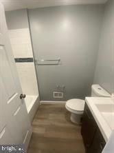 bathroom featuring toilet, baseboards, wood finished floors, and vanity