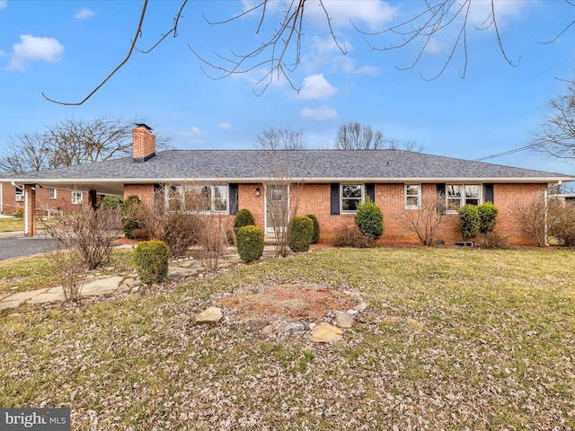 ranch-style home featuring brick siding, a chimney, a front lawn, and roof with shingles