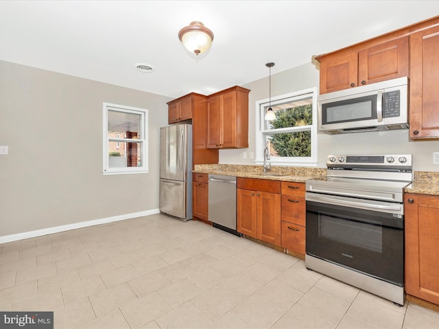 kitchen featuring appliances with stainless steel finishes, plenty of natural light, brown cabinets, and a sink