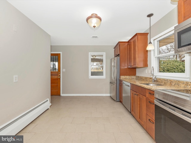 kitchen featuring brown cabinets, stainless steel appliances, a baseboard radiator, a sink, and light stone countertops