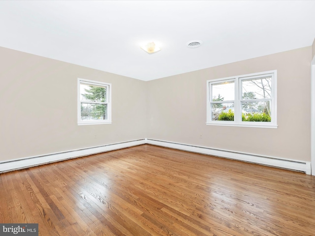 unfurnished room featuring a baseboard radiator, wood finished floors, and visible vents