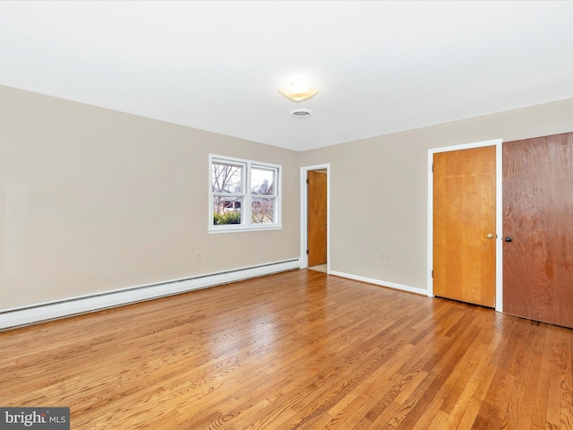 spare room with light wood-style floors, baseboards, and a baseboard heating unit