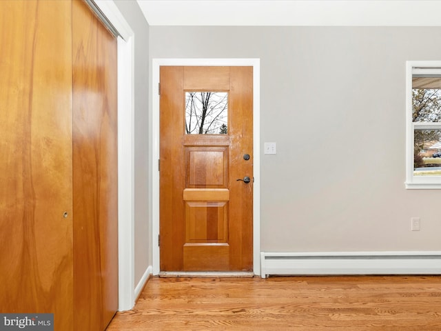 entryway with baseboard heating, light wood-style flooring, and a healthy amount of sunlight