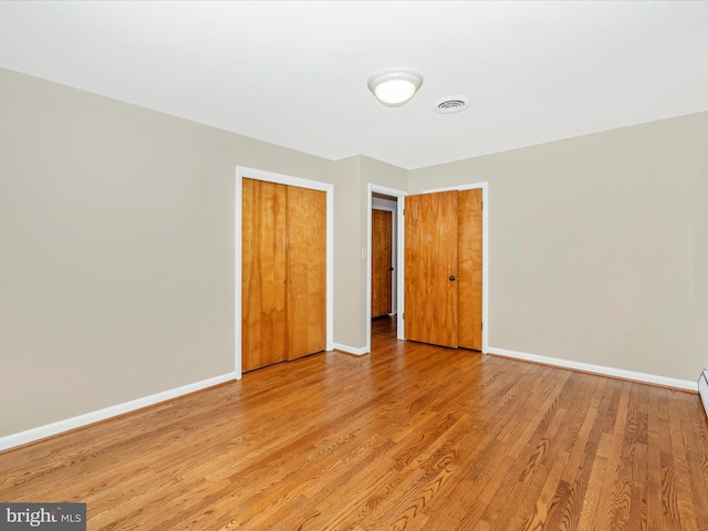 unfurnished bedroom with visible vents, light wood-style flooring, and baseboards