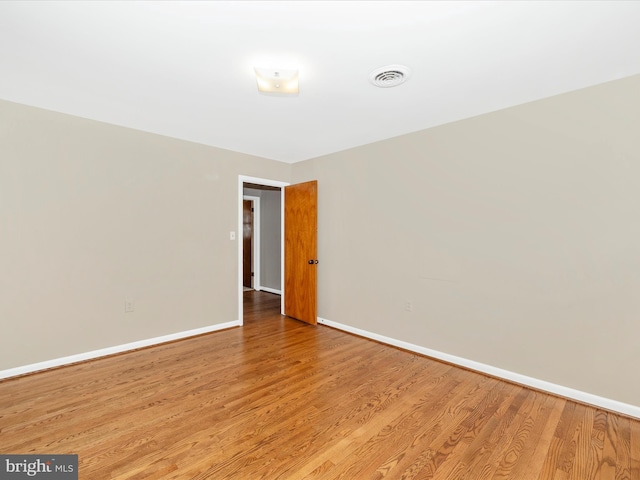 unfurnished room featuring visible vents, baseboards, and wood finished floors