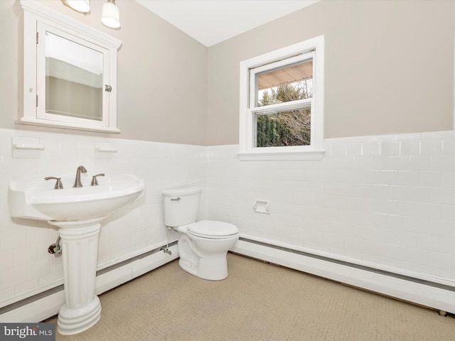 bathroom featuring toilet, a baseboard heating unit, tile walls, baseboard heating, and wainscoting