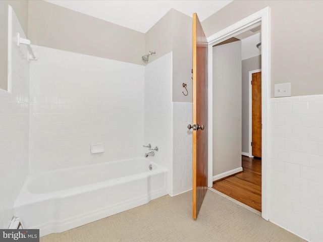 full bathroom with  shower combination, a wainscoted wall, tile patterned flooring, and tile walls