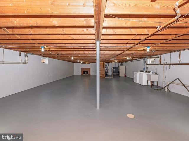 basement featuring washer and clothes dryer, a sink, and freestanding refrigerator