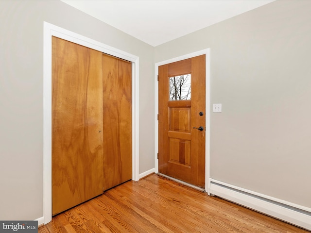 foyer with baseboard heating, light wood-type flooring, and baseboards