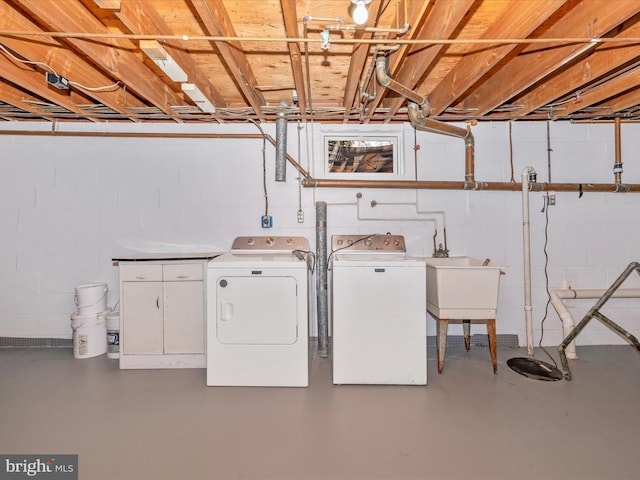 clothes washing area featuring separate washer and dryer, a sink, cabinet space, and concrete block wall