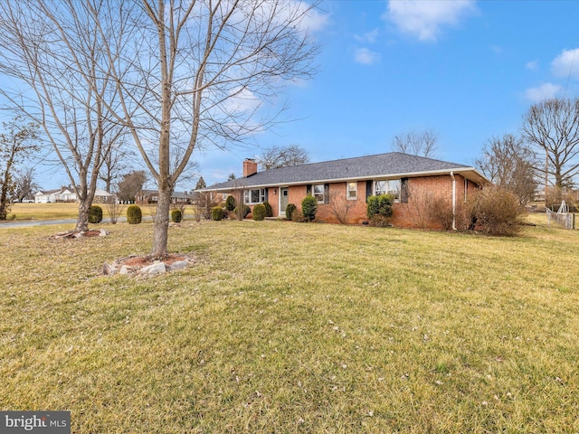 single story home with a chimney, a front lawn, and brick siding