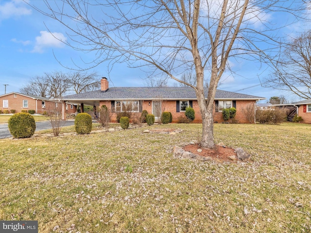 ranch-style home with a front yard, brick siding, and a chimney