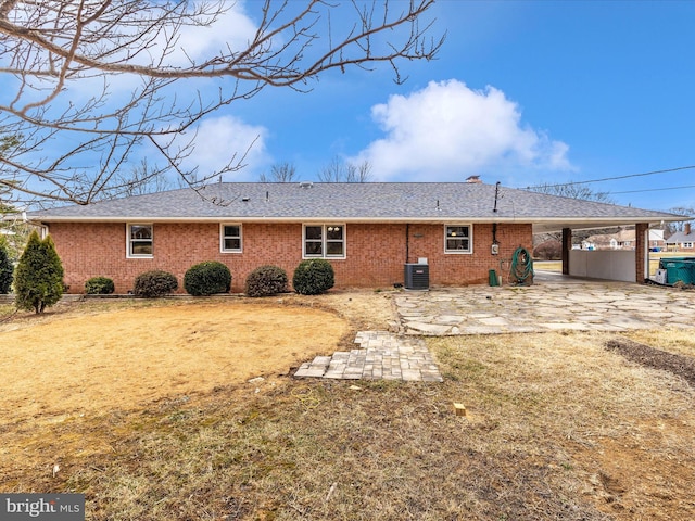 rear view of property featuring central AC, brick siding, driveway, a carport, and a patio area