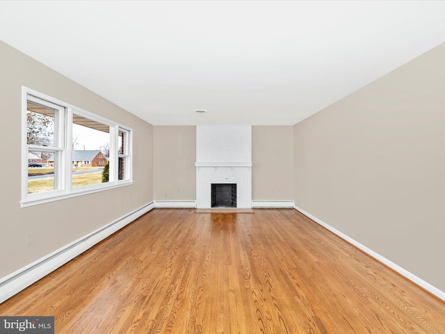 unfurnished living room featuring a baseboard radiator, a fireplace, and baseboards