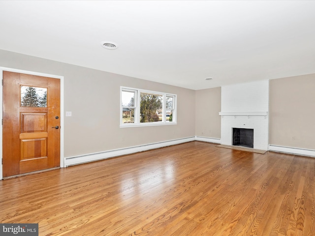 unfurnished living room featuring a brick fireplace, visible vents, light wood-style flooring, and baseboard heating