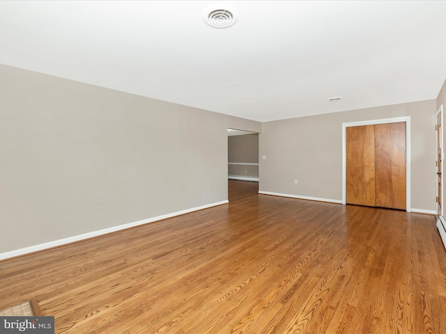 empty room featuring visible vents, baseboards, and wood finished floors