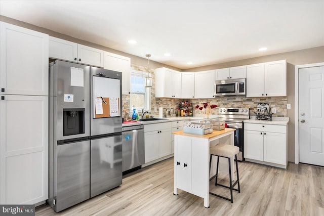 kitchen with appliances with stainless steel finishes, white cabinets, a sink, and tasteful backsplash