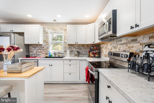 kitchen featuring stainless steel appliances, butcher block counters, white cabinetry, and a sink