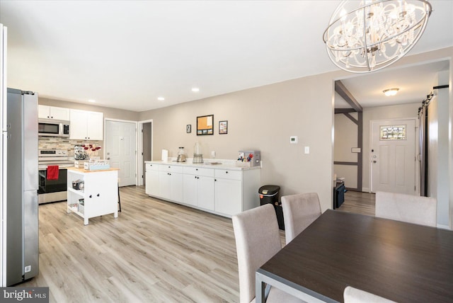 kitchen with stainless steel appliances, light countertops, light wood-style flooring, decorative backsplash, and white cabinets