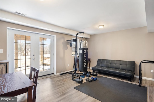 exercise area with baseboards, wood finished floors, and french doors