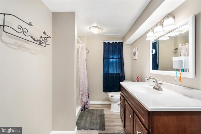 bathroom featuring baseboards, a shower with shower curtain, toilet, wood finished floors, and vanity