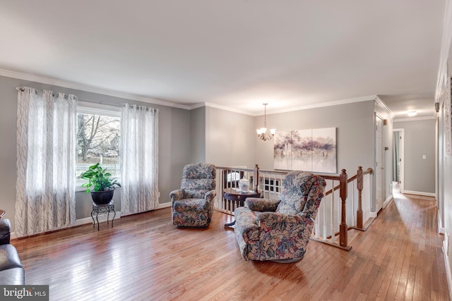 sitting room with baseboards, hardwood / wood-style flooring, ornamental molding, an upstairs landing, and a chandelier