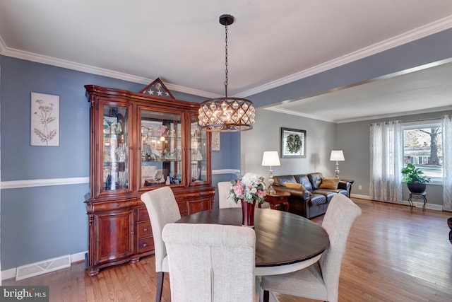 dining room featuring ornamental molding, wood finished floors, visible vents, and baseboards