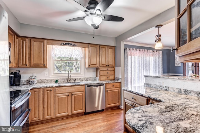 kitchen featuring light stone countertops, light wood-style floors, stainless steel appliances, and a sink