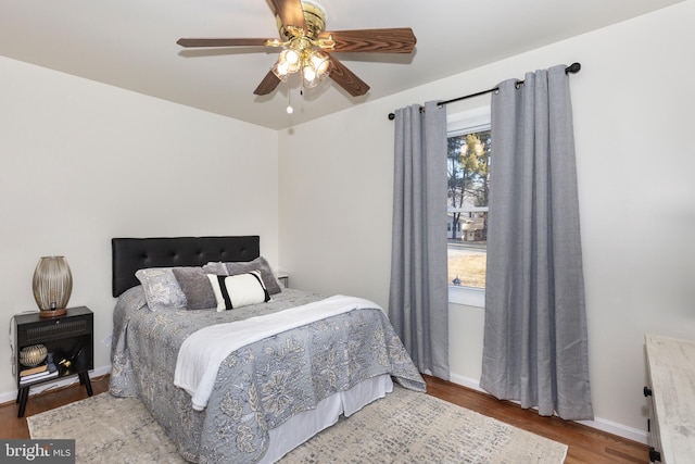 bedroom featuring a ceiling fan, baseboards, and wood finished floors