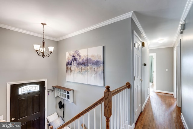 entrance foyer featuring a notable chandelier, ornamental molding, wood-type flooring, and baseboards