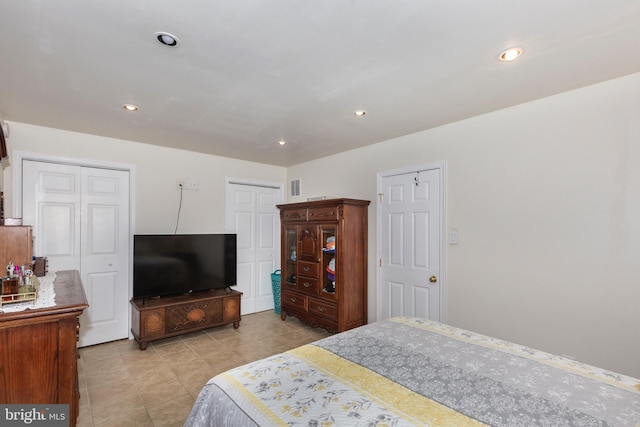 bedroom featuring multiple closets, recessed lighting, visible vents, and light tile patterned flooring