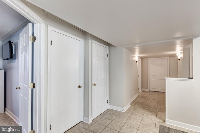 corridor with baseboards and light tile patterned flooring