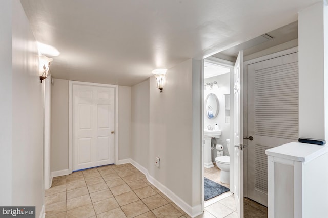 bathroom with a sink, toilet, baseboards, and tile patterned floors