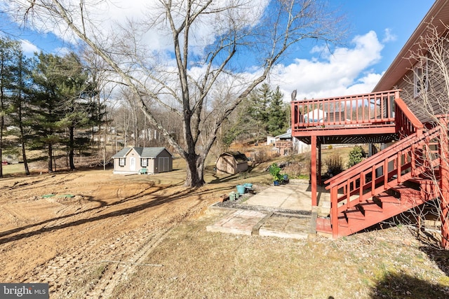 view of yard featuring an outbuilding, a patio, stairway, a wooden deck, and a storage unit