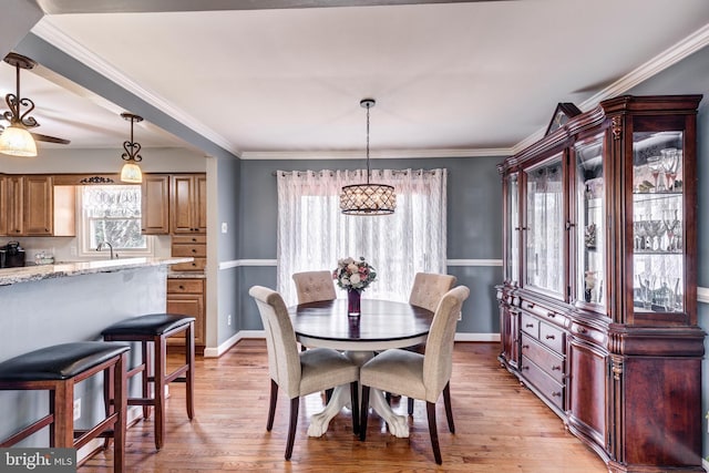 dining area with ornamental molding, baseboards, and light wood finished floors