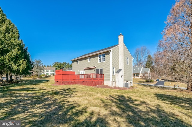 rear view of house with a wooden deck, a lawn, central AC unit, and a chimney