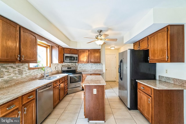 kitchen featuring a sink, backsplash, a center island, appliances with stainless steel finishes, and light countertops