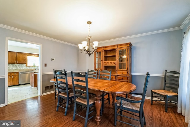 dining area with visible vents, baseboards, an inviting chandelier, crown molding, and light wood-type flooring