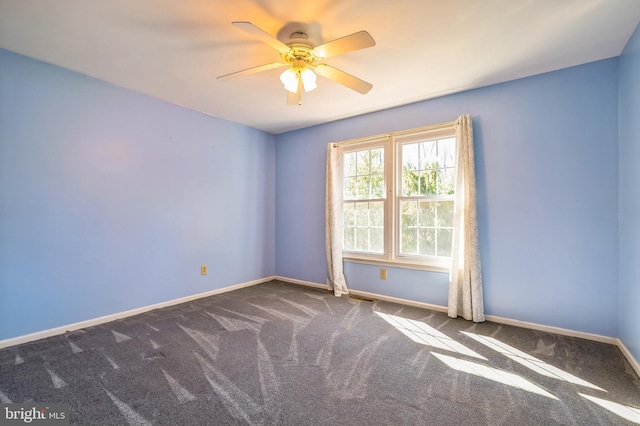 carpeted spare room with visible vents, a ceiling fan, and baseboards