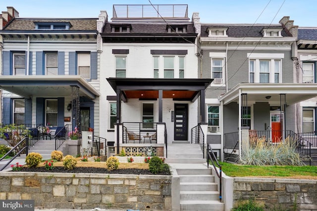 view of front of home featuring mansard roof, a shingled roof, and brick siding