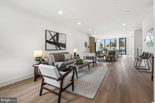 living room featuring baseboards, floor to ceiling windows, wood finished floors, and recessed lighting